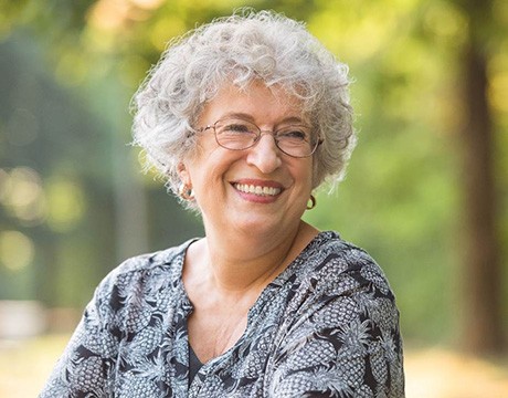 Senior woman with glasses smiling in the woods