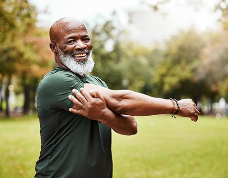 Senior man with beard outside doing stretches