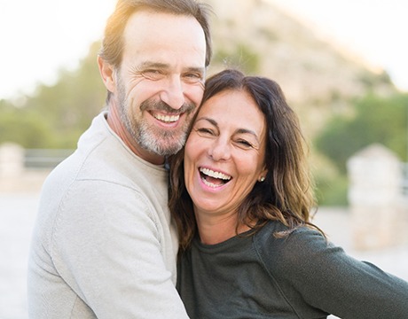 Man and woman smiling while hugging outside