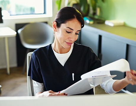 Dental team member looking at paperwork on clipboard