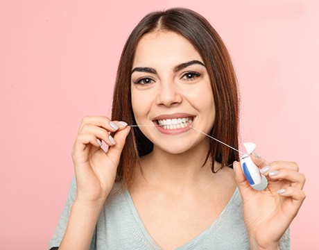 Woman smiling while flossing her teeth