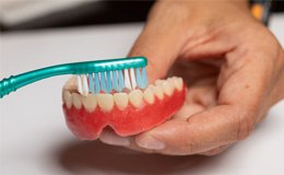 Man brushing his dentures