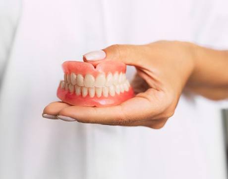 doctor holding dentures in Gainesville