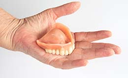 Person holding an upper denture