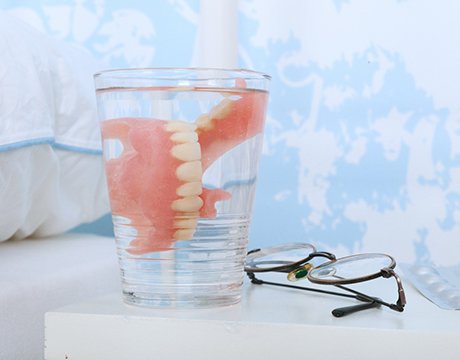 Closeup of dentures in Gainesville soaking in glass