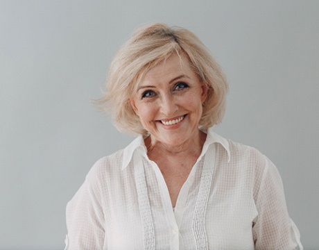 Senior woman in white blouse, happy she received implant dentures