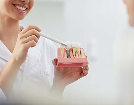 dentist showing a dental implant model to a patient