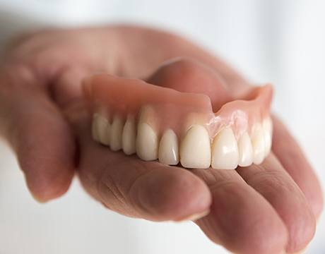 Hand holding a full denture