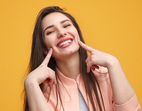 Young woman pointing to her smile.