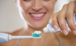 woman putting toothpaste on an electric toothbrush