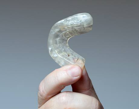 Hand holding a clear plastic occlusal splint