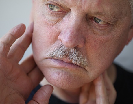 Image tag: older man with TMD touching jaw 
