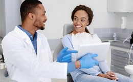 a dentist pointing at a tablet for a patient 