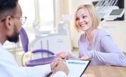 a woman smiling while talking with her dentist