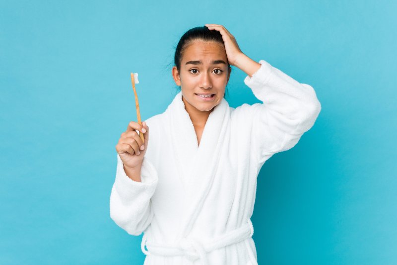 Woman looking nervous while holding a toothbrush