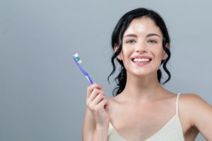 Smiling woman brushes her teeth as recommended by Gainesville dentist