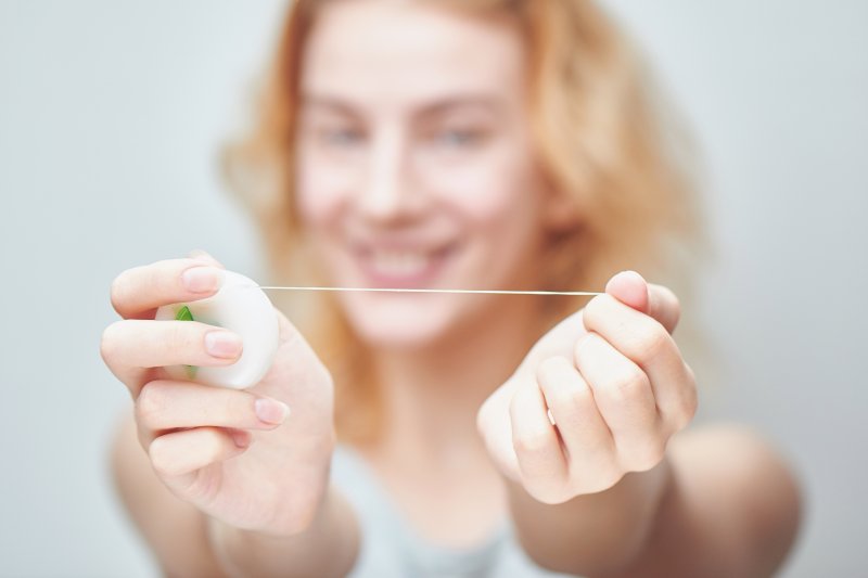 a woman smiling about flossing dental implants in Gainesville