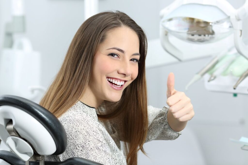 A woman giving a thumbs up at her dental appointment
