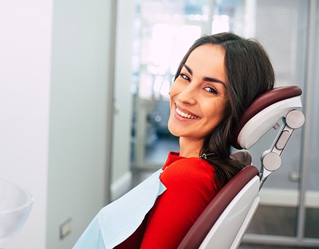 Woman in red shirt smiling in dental chair 