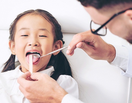 child getting their mouth examined by a dentist