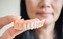 Woman holding her dentures