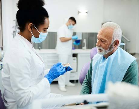 Dentist explaining cost of dentures in Gainesville to older patient