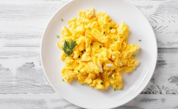 Scrambled eggs on white plate with garnish