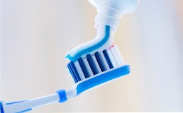 Putting toothpaste on a blue toothbrush
