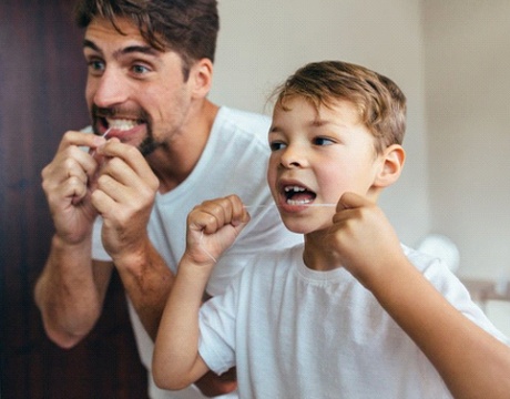 father and son flossing to prevent dental emergencies in Gainesville