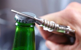 person opening a green bottle with a bottle opener